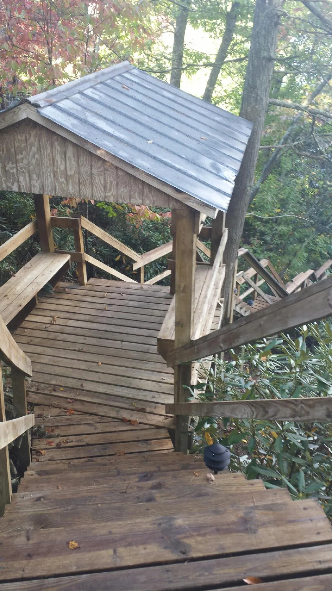 Metal roofed shelter over wooden steps on a wooded walkway — Skylight Repair & Installation work by our crew in Nevada